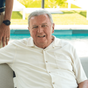 John Clarkson, founder of Clarkson Pools, smiling while seated near a luxury pool, reflecting on 35 years of excellence in pool design and outdoor living.